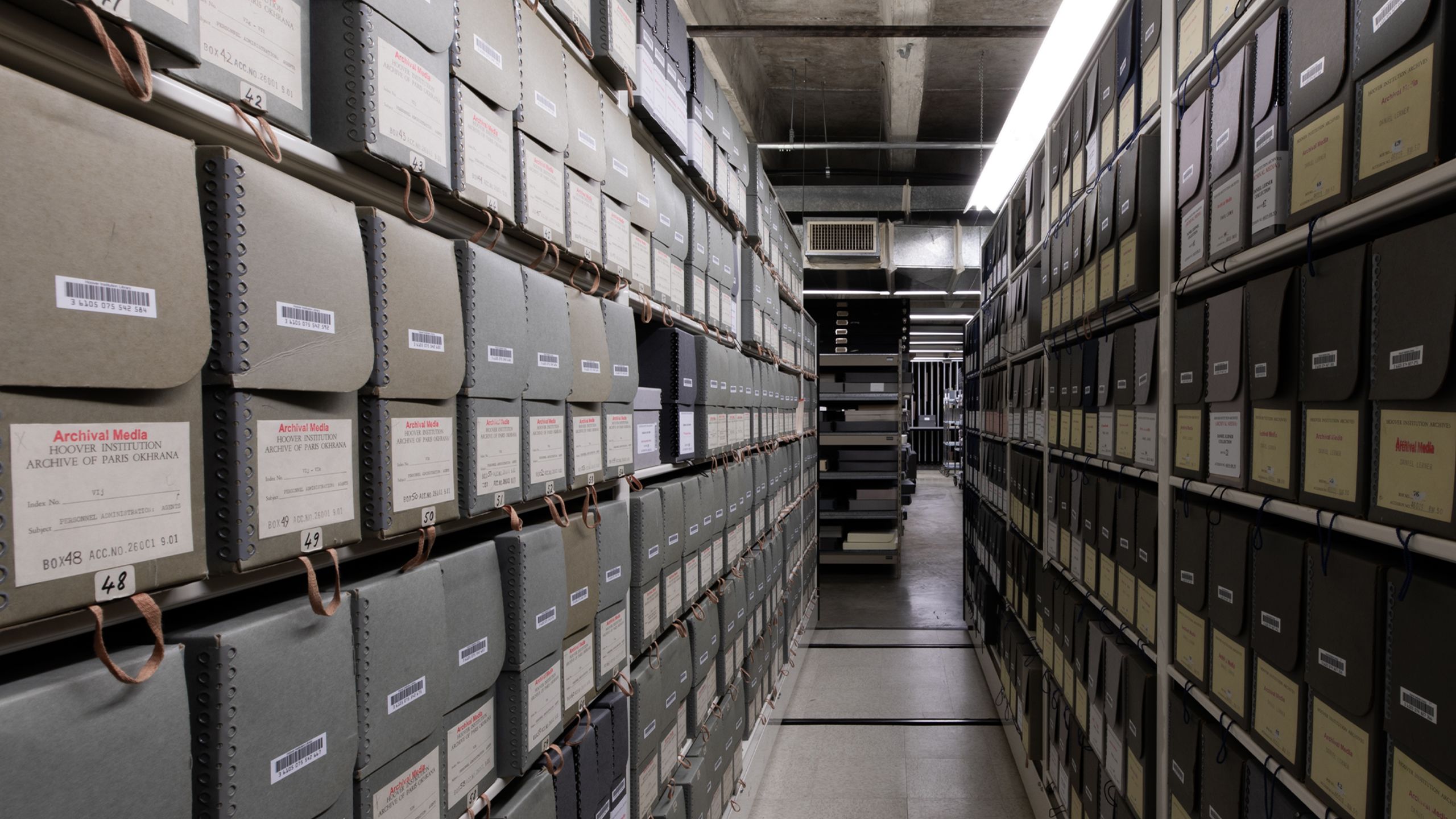 Color photograph showing rows of archival manuscript boxes on shelves in the closed stacks 