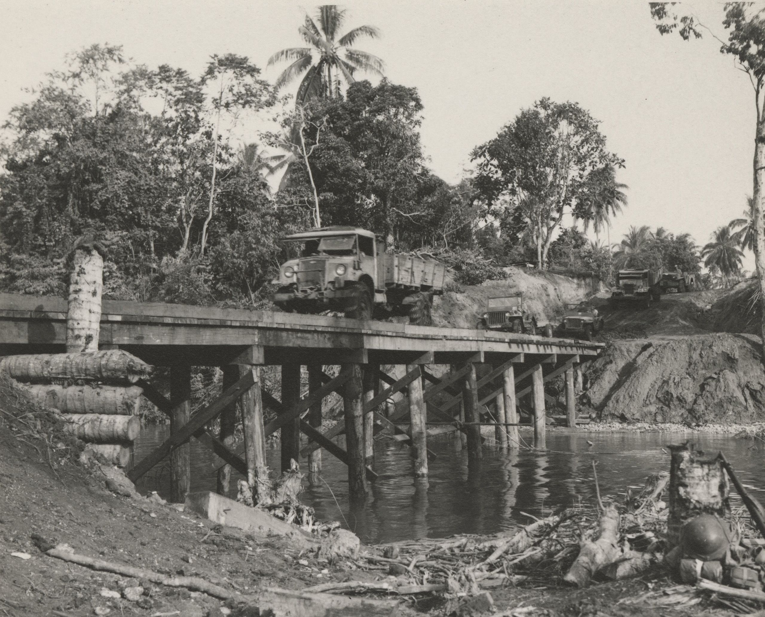 Australian trucks moving up to the front line over a bridge built by 78th Construction Battalion on the Bumi River, New Guinea, 1944.