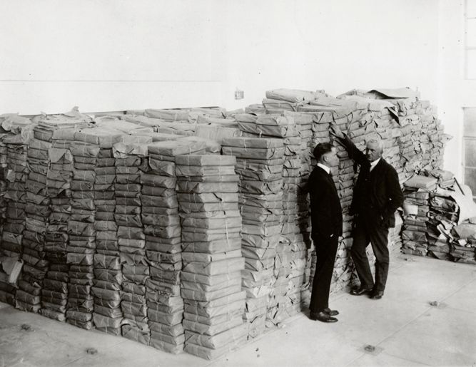 Black and white photograph of E. D. Adams and Ralph H. Lutz standing alongside unopened collection materials, circa 1924. From the Hoover Institution on War, Revolution and Peace Records, at the Hoover Institution Archives