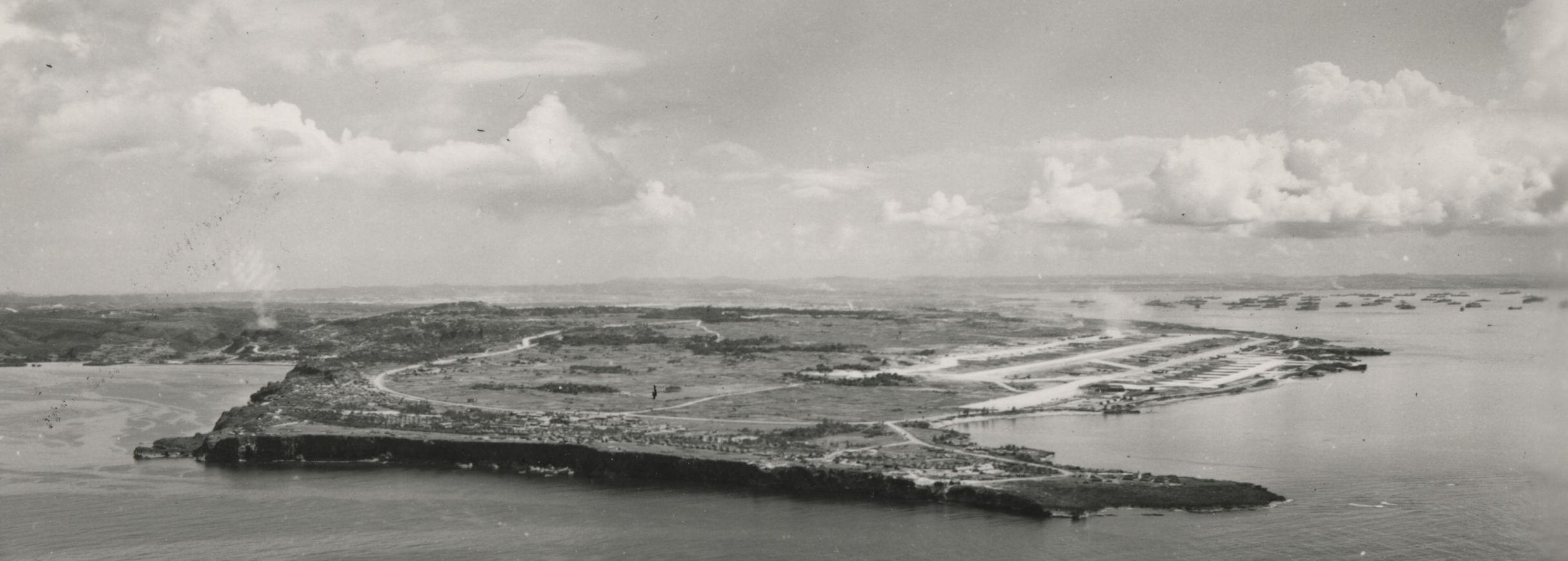 Black and white aerial photograph of Bolo Point (looking south) with Navy ships at anchor in Hagushi Bay, Okinawa, 1945. 