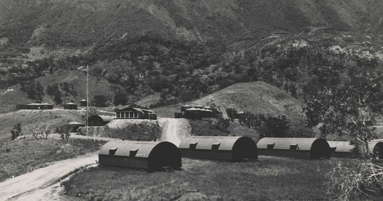 Black and white photograph of a military Camp with Quonset huts in the shadow of Mont Dore, 1945.