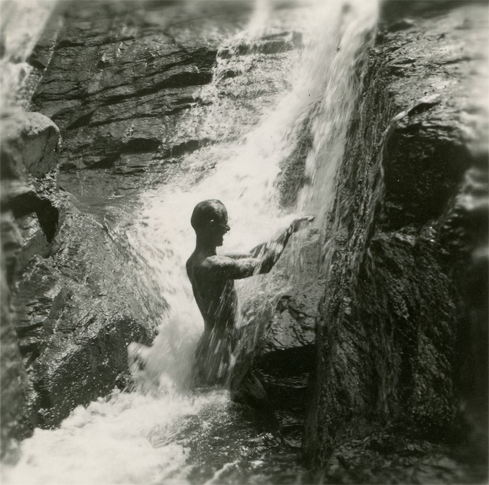 Black and white photograph of Seabee Al Perron showing in a natural waterfall on New Caledonia, 1944-1945.