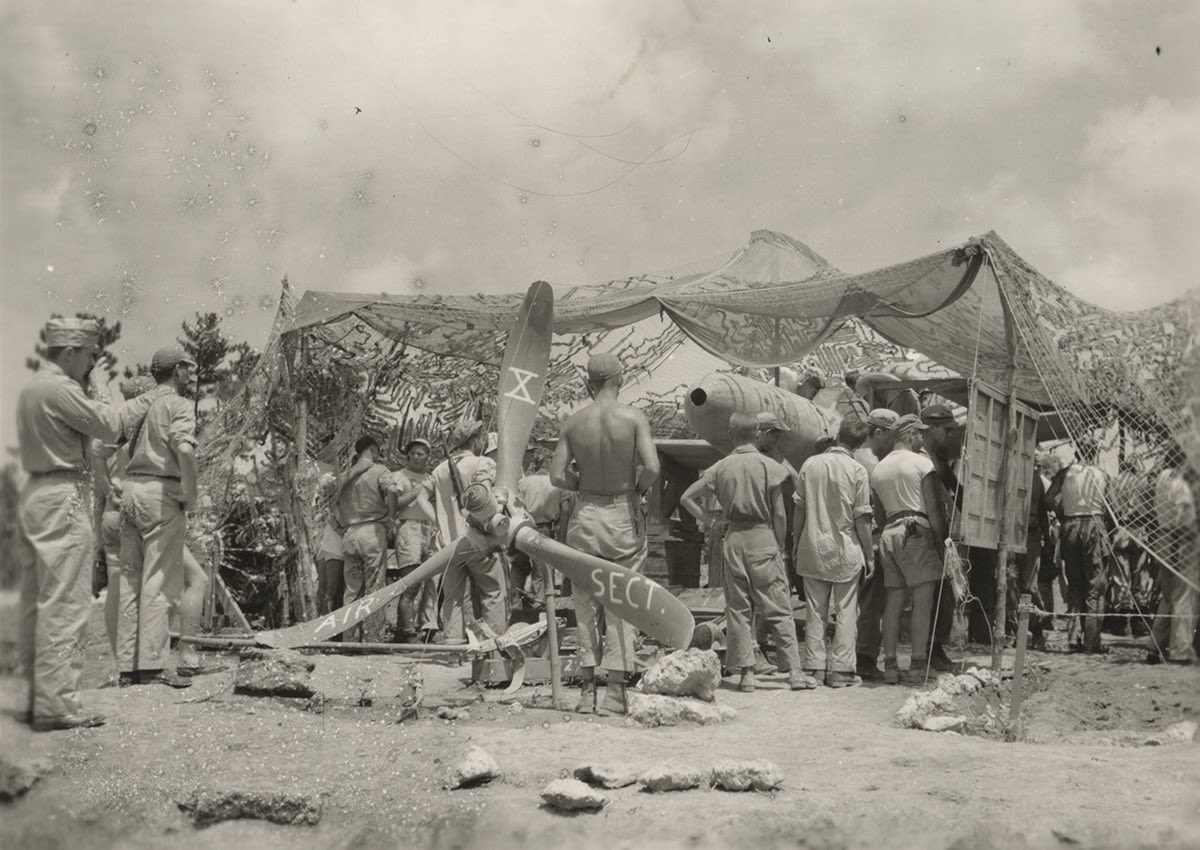 Black and white photograph of troops looking at a display of a captured Yokosuka MXY7 Ohka kamikaze aircraft on Okinawa, 1945.