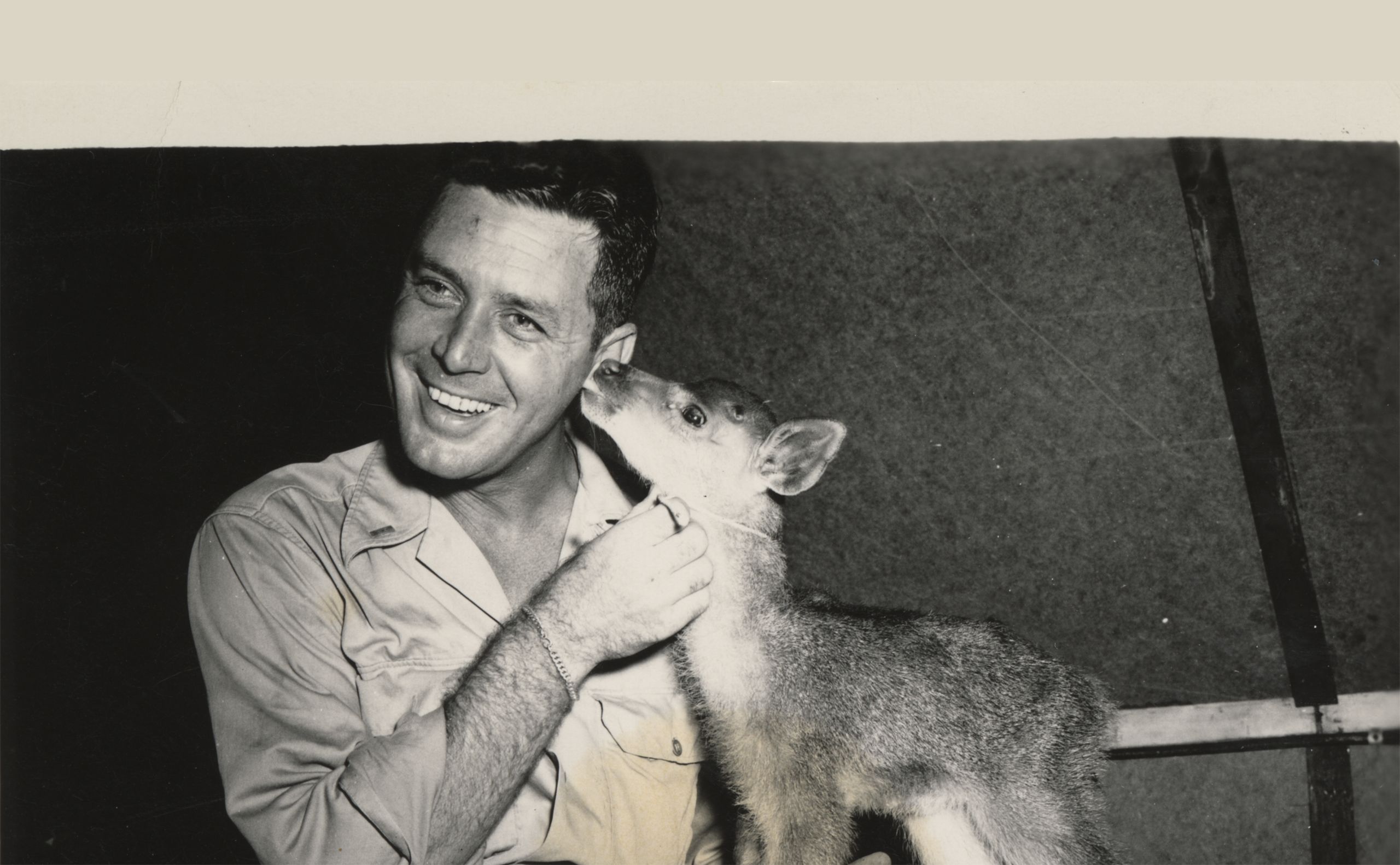 Black and white photograph of Father Kofflin receiving a kiss from Bambi, 1945.