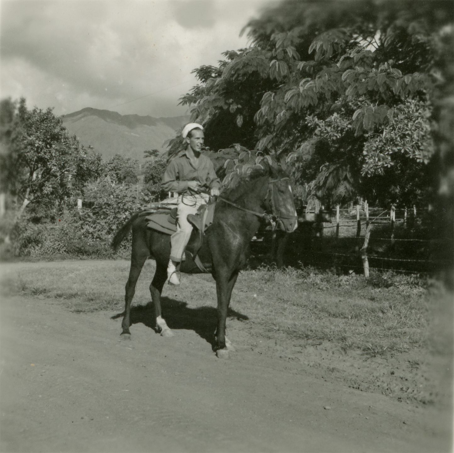 Black and white photograph of Ed Keegan riding a mule on New Caledonia, 1944-1945.