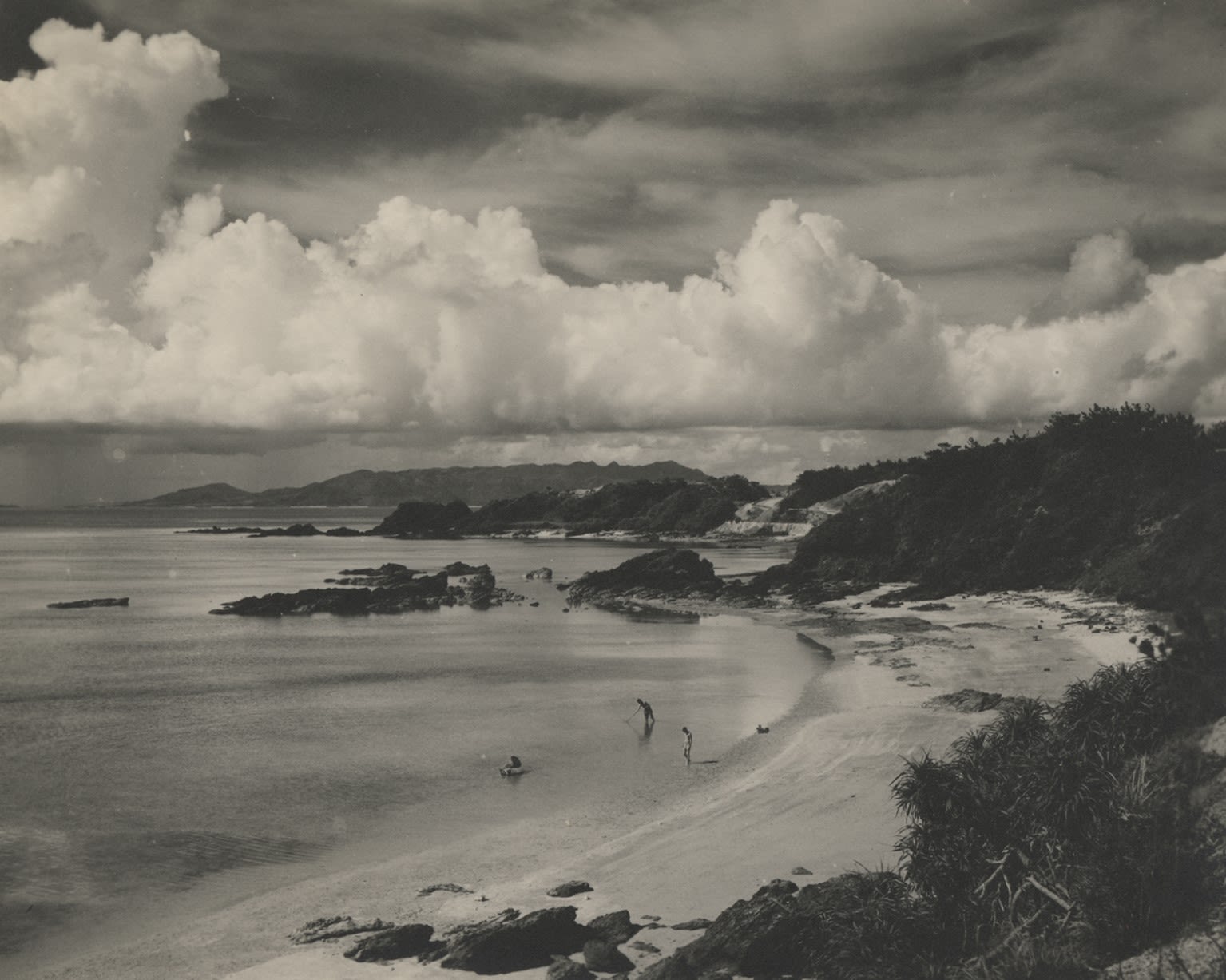Black and white photograph showing three men swimming at a beach on Okinawa, 1945.