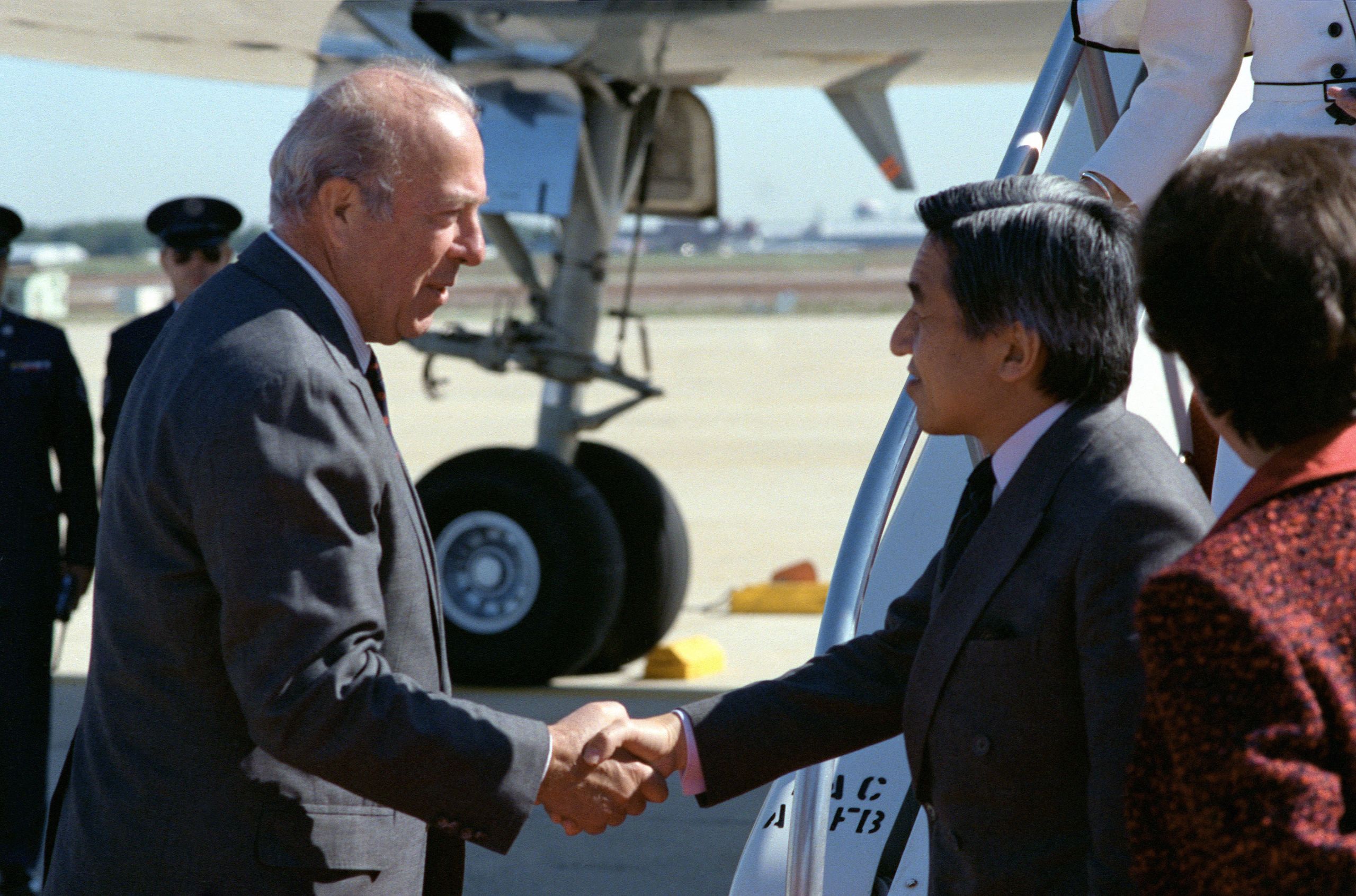 Color photograph of Secretary of State George P. Shultz greets Crown Prince Akihito of Japan upon the dignitary's arrival for a state visit, Andrews Air Force Base, Maryland. October 7, 1987 From the George Pratt Shultz Papers, Hoover Institution Archives